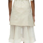 A person showcasing casual elegance in the 3.1 Phillip Lim Cascade Belted Combo Lace Shirt Dress, featuring a beige short-sleeve coat with a belt, paired with a white layered skirt adorned with delicate lace panels, viewed from the back.
