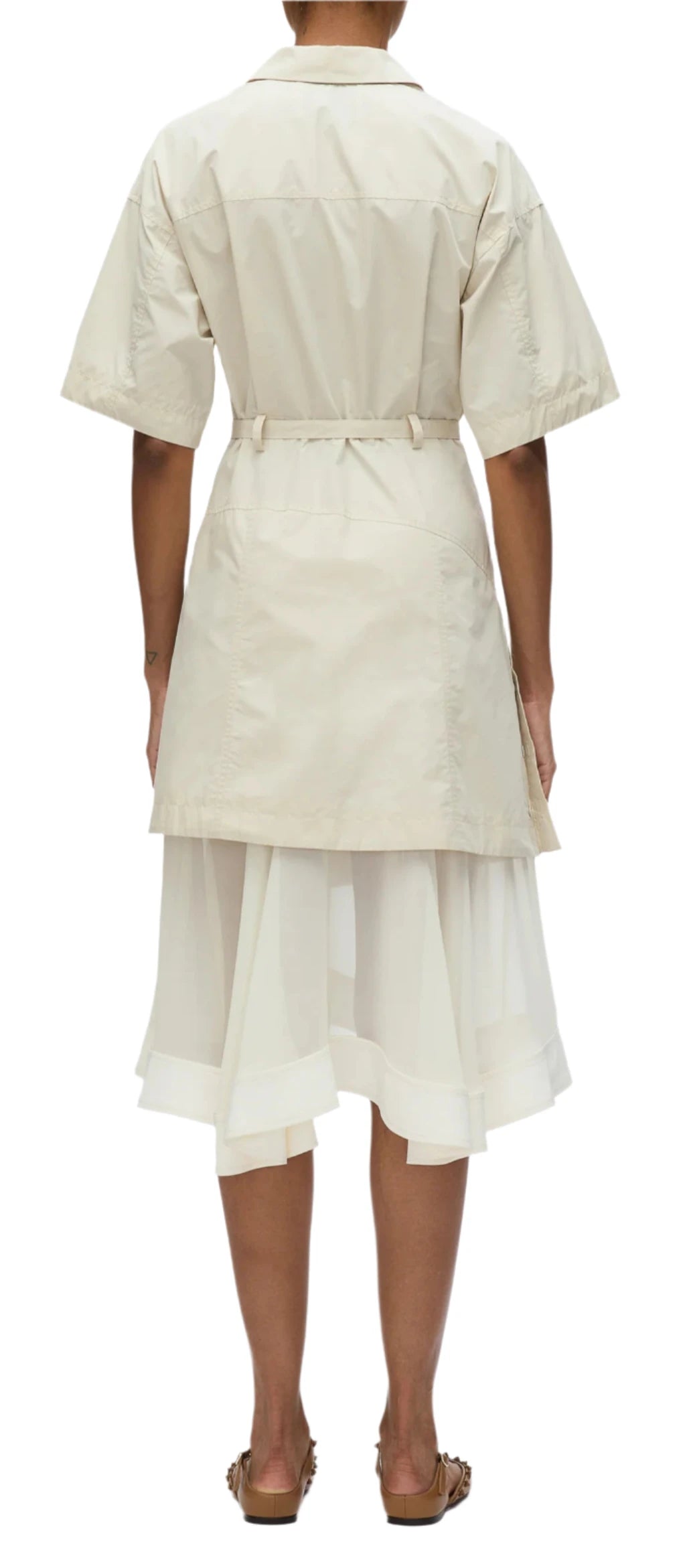 A person showcasing casual elegance in the 3.1 Phillip Lim Cascade Belted Combo Lace Shirt Dress, featuring a beige short-sleeve coat with a belt, paired with a white layered skirt adorned with delicate lace panels, viewed from the back.
