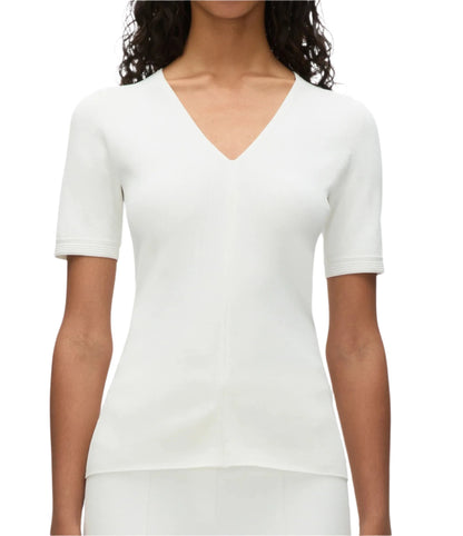 A person is shown wearing the 3.1 Phillip Lim Compact Rib V-Neck Top, a white short-sleeved piece that exemplifies wardrobe essentials with its flattering fit, set against a plain background and captured from the shoulders to the waist.