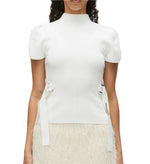 A person dressed in the 3.1 Phillip Lim Compact Rib Tulip Top, a white short-sleeve piece with puffed shoulders and side straps, paired with a textured skirt featuring a Tulip silhouette.