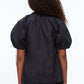 Person with curly hair wears the 3.1 Phillip Lim Ruched Sleeve V-Neck Top in a dark shade with dark denim jeans, shown from the back against a plain background.