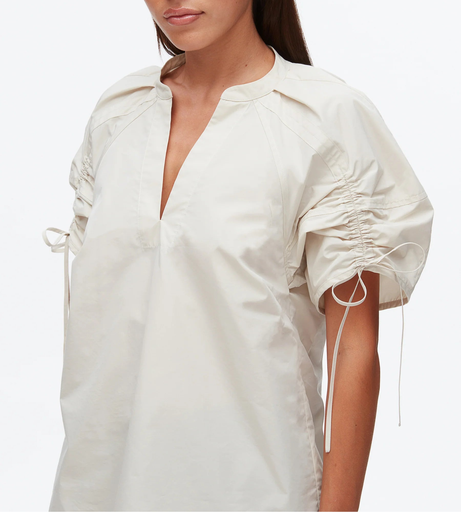 A woman models the 3.1 Phillip Lim Ruched Sleeve V-Neck Top in technical poplin, showcasing short sleeves with drawstring ruching, pictured from shoulders to hips against a plain background.