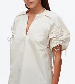 A woman models the 3.1 Phillip Lim Ruched Sleeve V-Neck Top in technical poplin, showcasing short sleeves with drawstring ruching, pictured from shoulders to hips against a plain background.