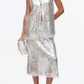 A woman wears the 3.1 Phillip Lim Sequin Flounce Tank with Bows, paired with a matching skirt featuring a lace-trimmed organza hem, and accessorizes with a white clutch and white block-heel shoes.