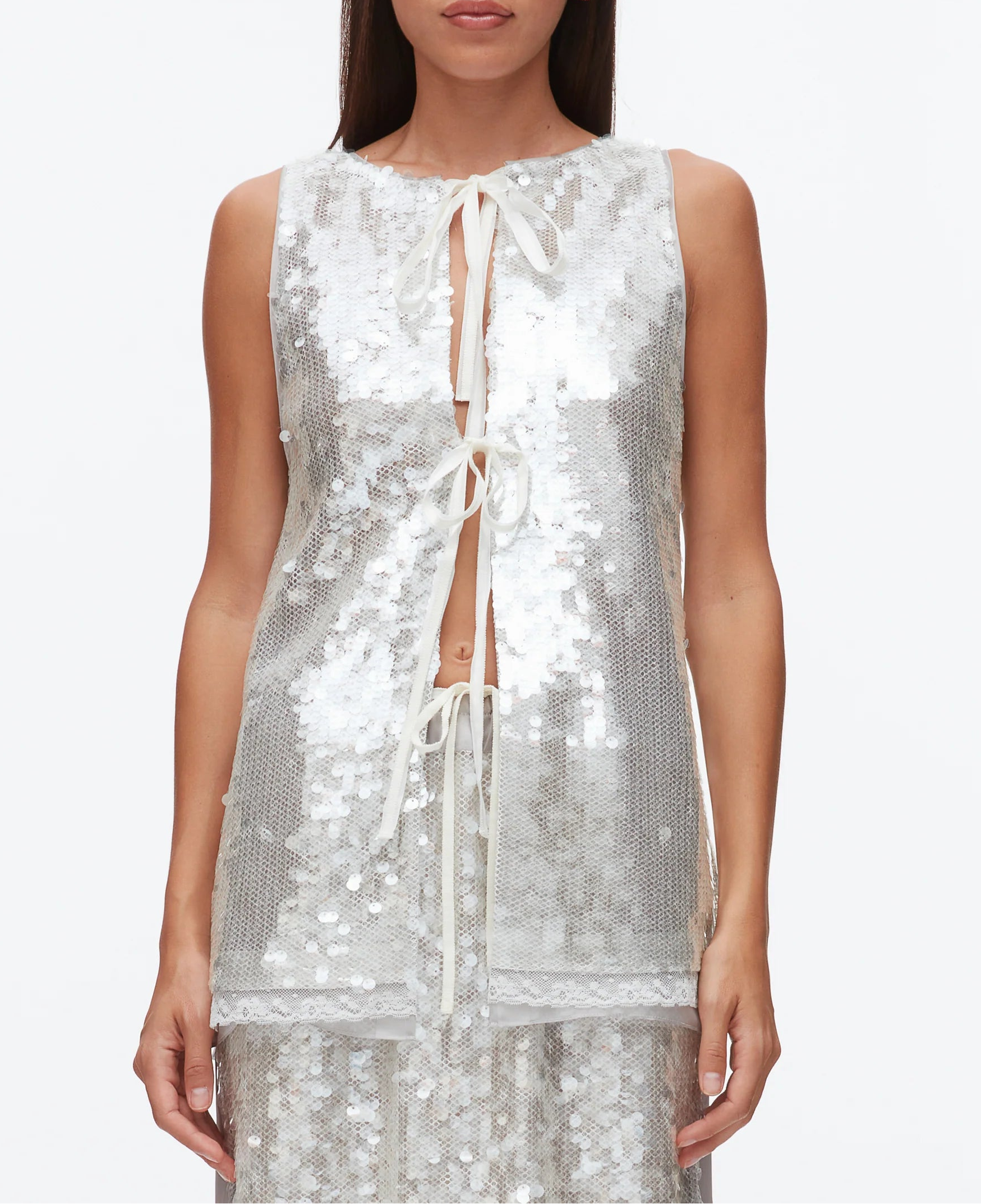 A woman wears the 3.1 Phillip Lim Sequin Flounce Tank with Bows over a matching skirt, featuring silver sequins, front tie bows, and a lace-trimmed organza hem, set against a plain white background.