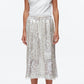 A woman faces forward wearing a white short-sleeve top, light blue sneakers, and the 3.1 Phillip Lim Sequin Pull On Skirt—a silver sequin midi skirt with a drawstring waistband.