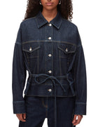 A person wears the 3.1 Phillip Lim Denim Boxy Jacket, featuring front pockets, button closure, and a waist tie, styled with matching denim pants for a coordinated look.