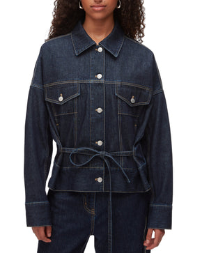 A person wears the 3.1 Phillip Lim Denim Boxy Jacket, featuring front pockets, button closure, and a waist tie, styled with matching denim pants for a coordinated look.