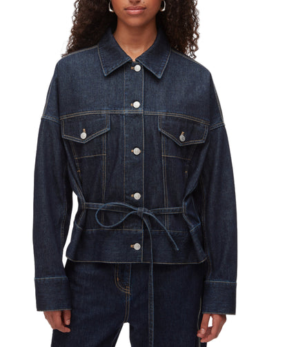 A person wears the 3.1 Phillip Lim Denim Boxy Jacket, featuring front pockets, button closure, and a waist tie, styled with matching denim pants for a coordinated look.