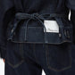 A person seen from behind wears a boxy indigo cotton denim jacket by 3.1 Phillip Lim, belted at the waist, with the label partially tucked into the waistband.