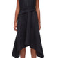 A woman in the Ruched Handkerchief Dress by 3.1 Phillip Lim, a sleeveless black midi made from technical poplin with a handkerchief hemline, paired with black loafers, stands against a plain background.