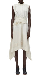 A person wears the 3.1 Phillip Lim Ruched Handkerchief Dress, an off-white sleeveless midi in technical poplin with a wrap waist and handkerchief hem, paired with black ankle boots.