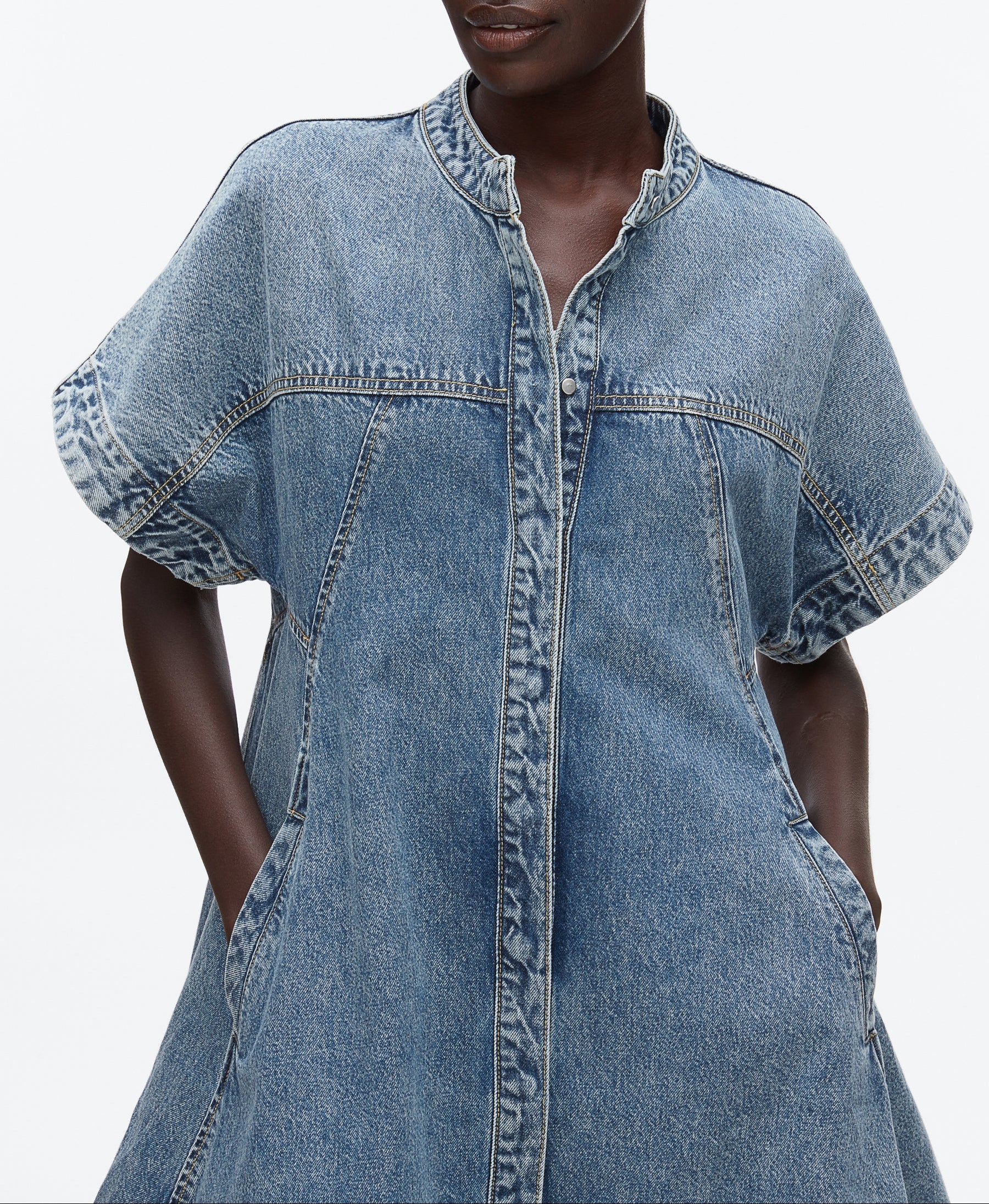 A model wears the 3.1 Phillip Lim Trapeze Light Denim Dress, a short-sleeve style with front seams, side pockets, and a trapeze silhouette, shown from shoulders to above the knees.