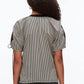 A person with long curly hair is seen from the back, wearing a 3.1 Phillip Lim Ruched T-Shirt with Combo Panel Back and dark jeans against a plain background.