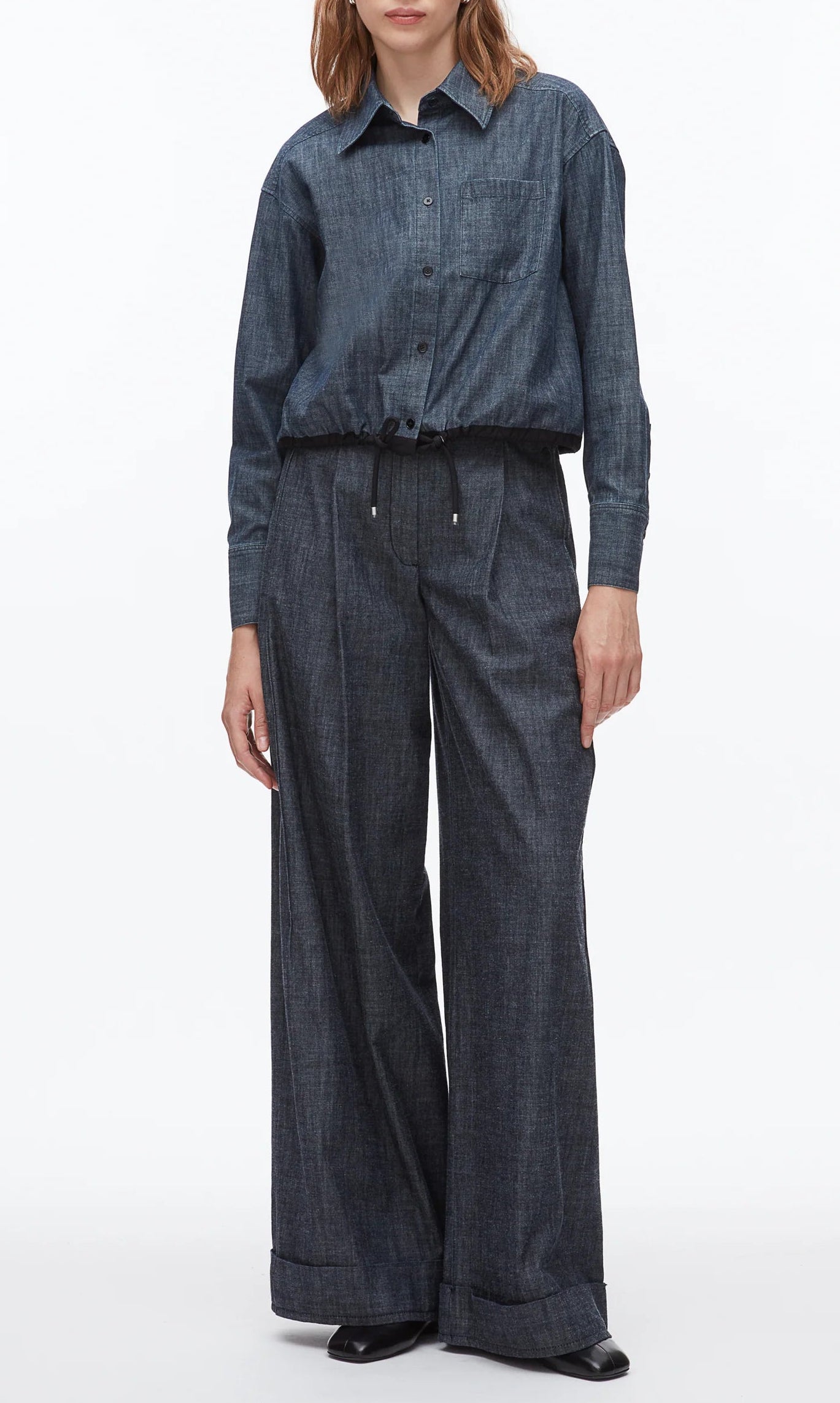 Wearing the 3.1 Phillip Lim Denim Cropped Shirt with a drawstring hem, tucked into high-waisted wide-leg jeans and styled with black shoes creates a modern silhouette.
