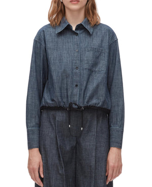A person models the 3.1 Phillip Lim Denim Cropped Shirt, featuring a drawstring hem, paired with matching denim pants to showcase a modern silhouette against a plain background.