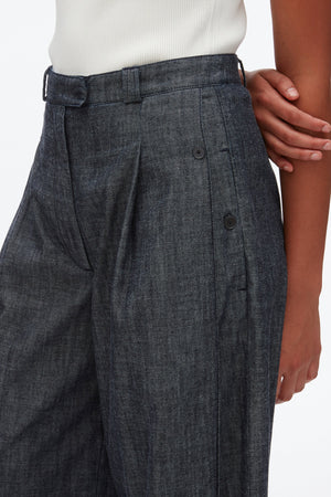 A person wearing 3.1 Phillip Lim's Denim Double Pleat Wide Leg Pant in dark denim, paired with a white ribbed top, shown from waist to mid-thigh.