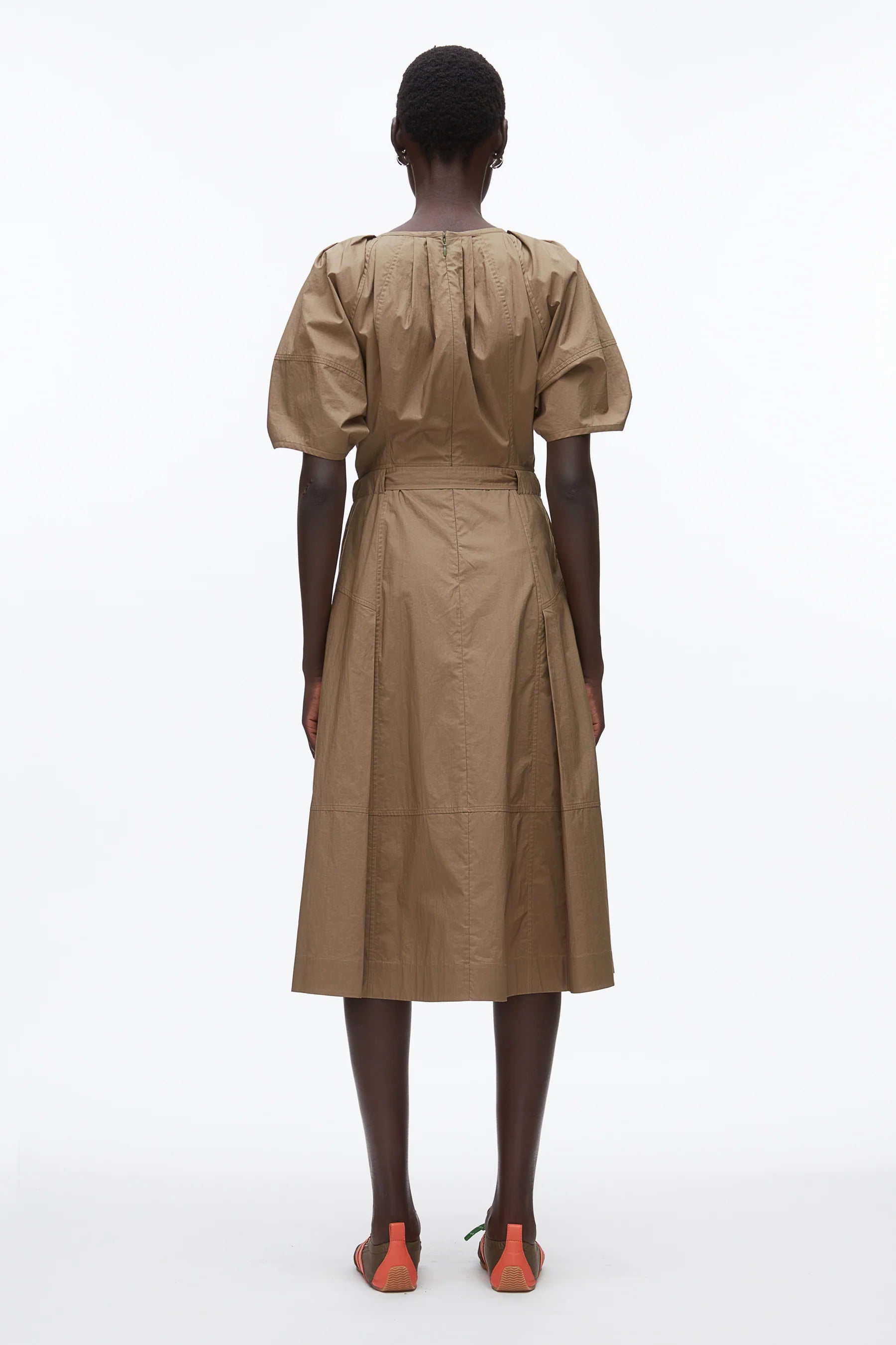 A person stands facing away, wearing the 3.1 Phillip Lim Ruched Sleeve Midi Dress paired with flat sandals with orange accents, set against a plain white background.