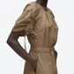 A person wears the 3.1 Phillip Lim Ruched Sleeve Midi Dress, a belted, short-sleeve, light brown cotton poplin dress with gathered details and hands in pockets, against a plain white background.