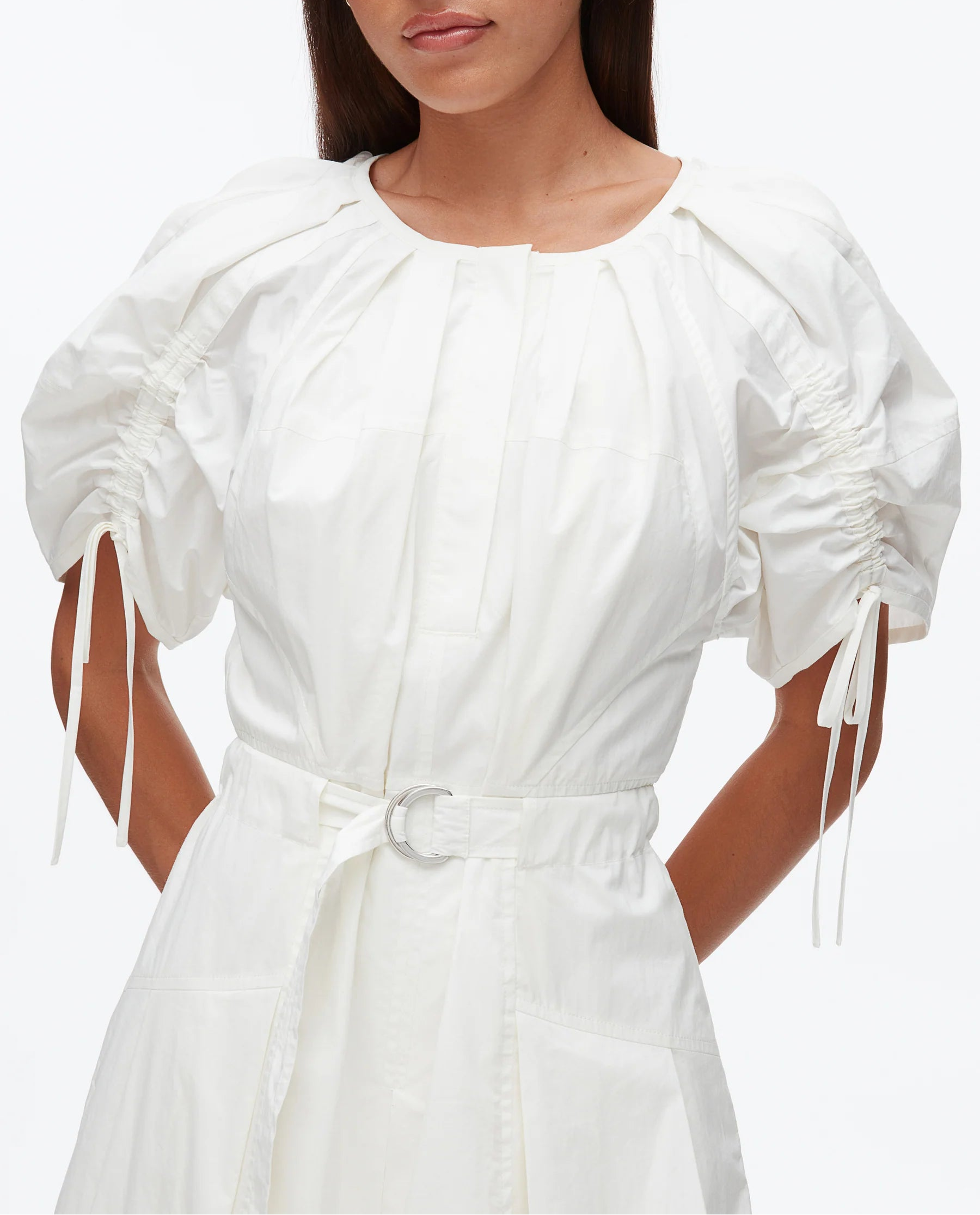 A woman models the 3.1 Phillip Lim Ruched Sleeve Midi Dress, featuring white cotton poplin, puffed short sleeves, ruched details, a round neckline, and a D-ring belt, set against a plain background.