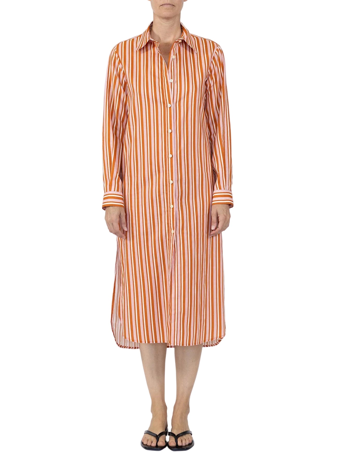 A person wearing the Callas Milano Elissa Long Shirtdress in orange and white market stripes stands facing the camera, paired with black flip-flops.