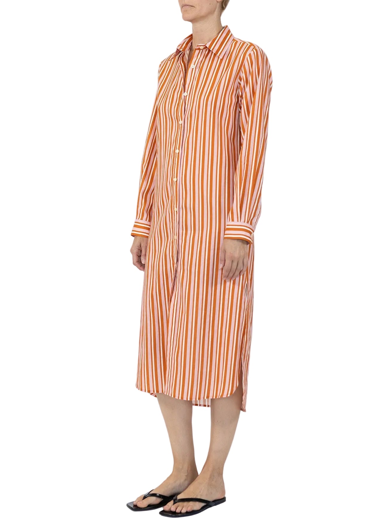 A person stands against a plain background, effortlessly showcasing the Callas Milano Elissa Long Shirtdress in orange and white stripes with black flip-flops for a chic, stylish look.
