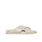 The Emi Slides by Anine Bing are beige flat sandals with padded crisscross straps and a flat sole, finished with a small metallic detail near the heel.