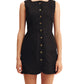 A woman wearing the POSSE Emma Mini Dress—a sleeveless black linen dress with a high neckline, front buttons, and two large front pockets—stands against a white background.