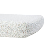 The Quincy Mae Bamboo Crib Sheet features a small floral print in muted green, yellow, and red on white. Shown fitted on a mattress, it's perfect for soft and gentle baby bedding.