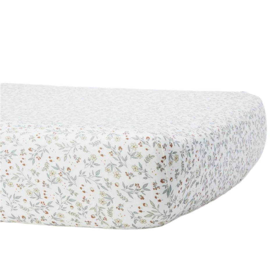 The Quincy Mae Bamboo Crib Sheet features a small floral print in muted green, yellow, and red on white. Shown fitted on a mattress, it's perfect for soft and gentle baby bedding.