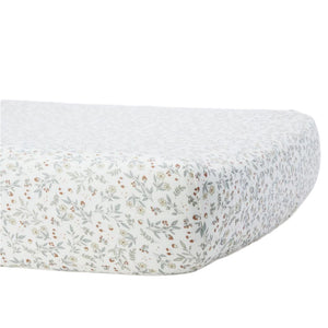 The Quincy Mae Bamboo Crib Sheet features a small floral print in muted green, yellow, and red on white. Shown fitted on a mattress, it's perfect for soft and gentle baby bedding.