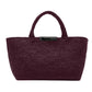 The Proenza Schouler East West Raffia Chelsea Tote is a structured handbag in dark burgundy with two handles and a black rectangular label on the front, effortlessly combining style and sophistication.