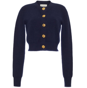 The Cara Cara Ellery Cardigan is a navy blue, crewneck sweater with long sleeves and gold floral buttons down the front, shown on a white background.