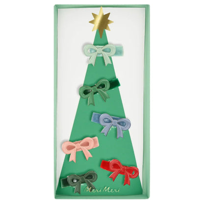 A set of six Meri Meri Enamel Bow Hair Clips in multicolored velvet, displayed on a tree-shaped cardboard backing featuring a golden star at the top.