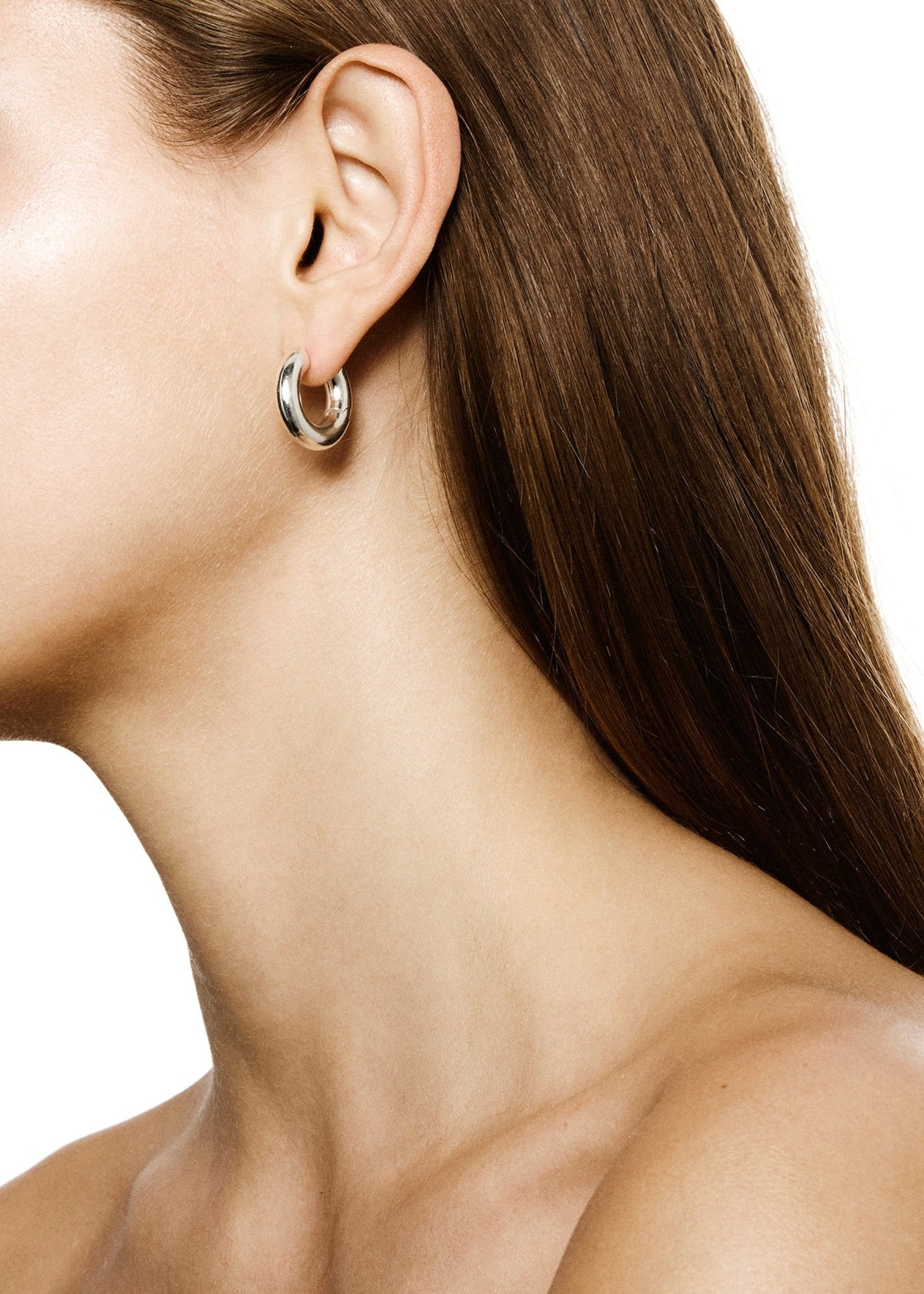 Close-up of a person's ear adorned with the LIÉ STUDIO Esther Earrings made from 925 Sterling silver. The person, with long, straight brown hair, is shown from the side against a plain white background. These elegant statement earrings by Lie Studio add a touch of sophistication.