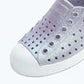 Close-up of the Kids’ Jefferson Bio-Bling™ by Native Shoes—a gray slip-on water-friendly shoe featuring black ventilation holes and a white rubber toe cap, crafted from lightweight EVA—shown on a light background.