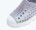 Close-up of the Kids’ Jefferson Bio-Bling™ by Native Shoes—a gray slip-on water-friendly shoe featuring black ventilation holes and a white rubber toe cap, crafted from lightweight EVA—shown on a light background.