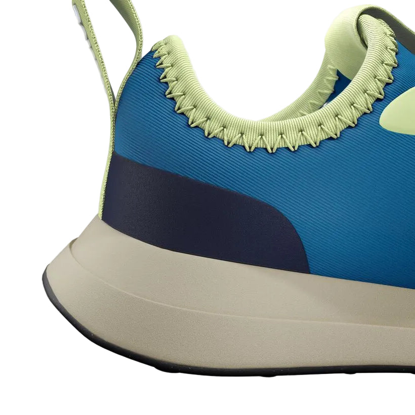 Close-up of the heel and side of a blue Kids’ Robbie Dash Sneaker by Native Shoes with green accents, featuring breathable mesh, a beige midsole, and a black outsole, viewed from the left.