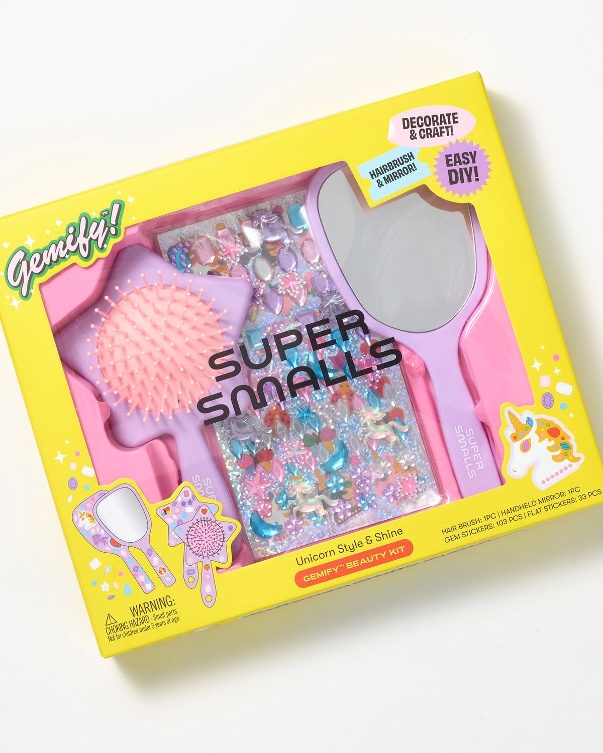 The Super Smalls Unicorn Style & Shine Gemify Beauty Kit features a sparkly brush, mirror, and decorative gems for DIY crafting in vibrant yellow packaging with purple and pink accents—perfect for kids.