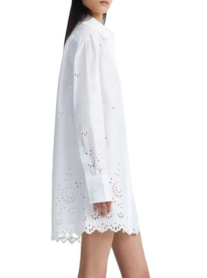 A person is wearing a white, long-sleeved Altuzarra Morton Dress with broderie anglaise and scalloped edges. The image shows a side view of the outfit.