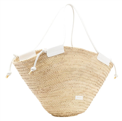 The Altuzarra Basket Tote by Altuzarra is a handmade natural woven straw basket tote that features sleek white leather straps and a convenient drawstring closure.