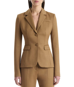A person wearing the Altuzarra Fenice Jacket, expertly tailored in a camel-colored virgin wool blend with matching pants, stands against a plain background.