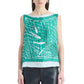 A woman wearing the Siggi Top by Altuzarra—a sleeveless green silk top featuring a white and black abstract net pattern and a wide neckline—paired with black leather pants.