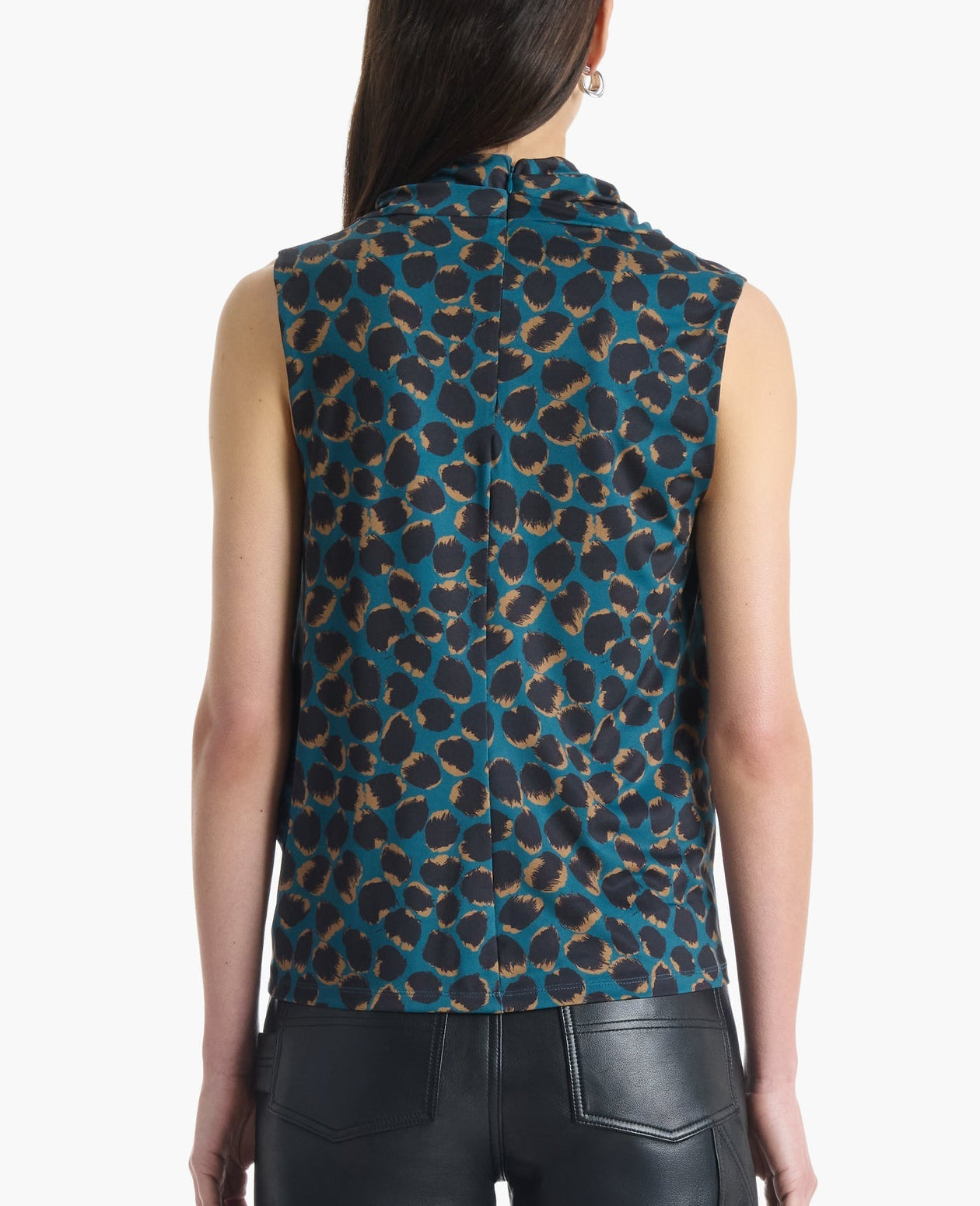 A model is shown from the back against a white background, wearing the Altuzarra Holt Top—a sleeveless blue and brown leopard print design with a draped neckline—paired with black leather pants. The top’s relaxed silhouette adds effortless style to the ensemble.