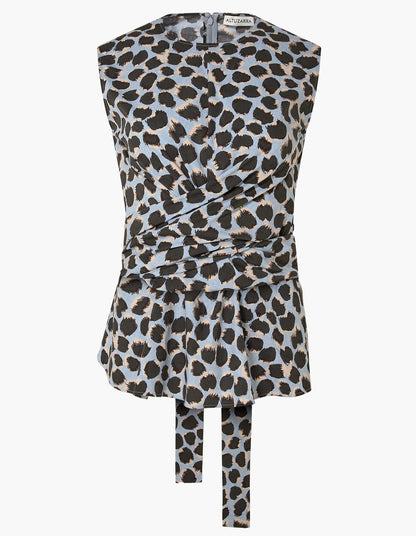The Tizzy Top by Altuzarra is a sleeveless piece showcasing a blue, black, and beige leopard print. It features a round neckline, a cinched waist with belted detail, and long fabric ties at the front.