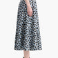 A woman stands in profile against a white background, wearing the Altuzarra Varda Skirt—a blue and black leopard print A-line midi skirt—paired with black high-heeled sandals.