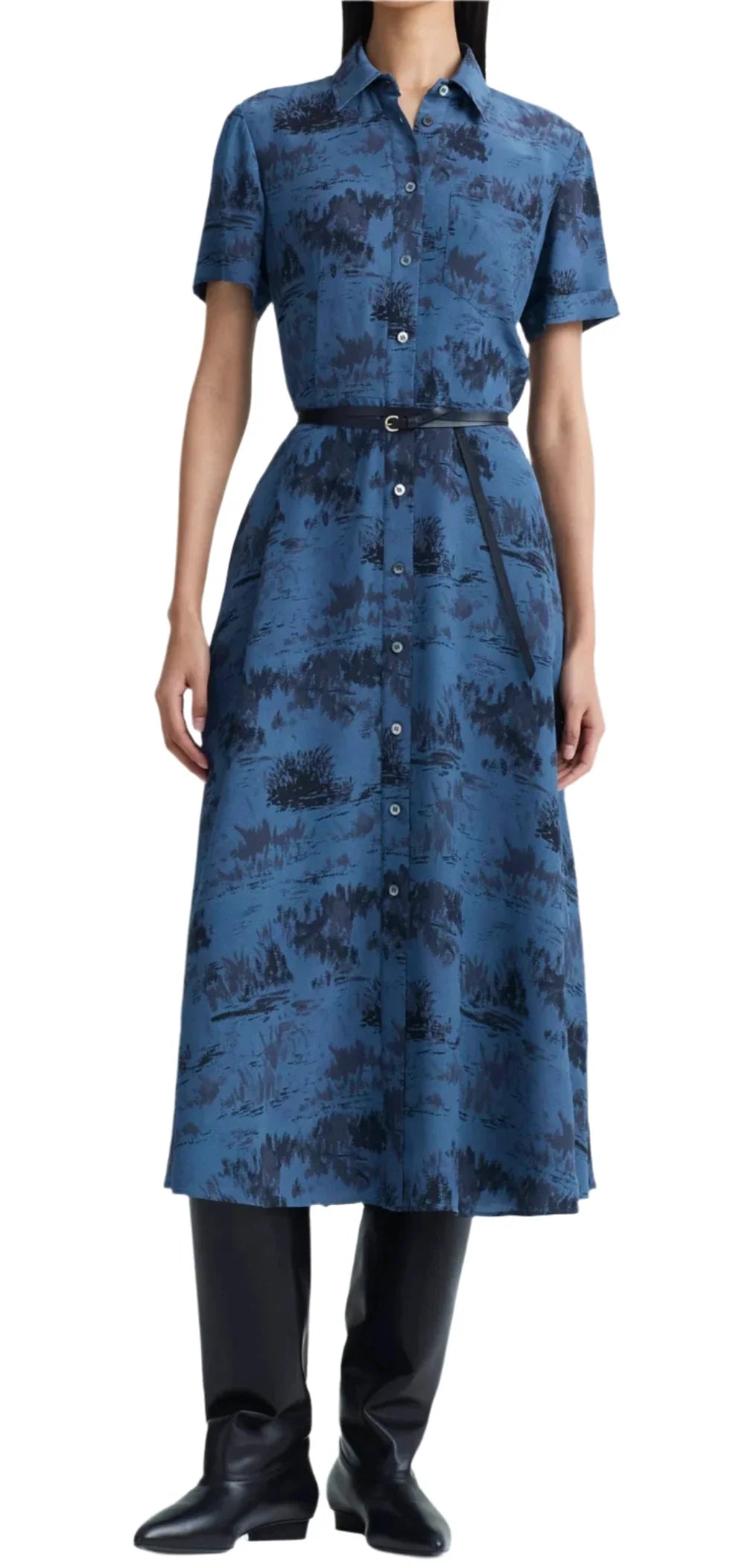 A person is wearing an Altuzarra Kiera dress with a landscape pattern, cinched elegantly with a leather waist belt, paired perfectly with black boots.