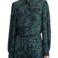 Person wearing a long-sleeved, dark green patterned Altuzarra Patsy Top with bishop sleeves and a matching skirt with large buttons on the side.