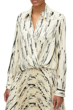 A person dressed in the 3.1 Phillip Lim Abstract Wood Grain Crossover Drape Blouse and a matching skirt, ideal for high summer with its breezy elegance.