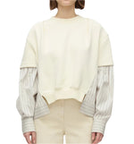 A person wears the 3.1 Phillip Lim Sweatshirt with Poplin Combo in cream organic cotton over a striped shirt, paired with beige pants, against a plain background.